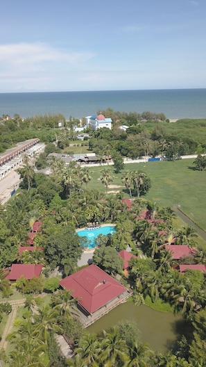 An aerial view of a resort with a swimming pool, palm trees, and a view of the sea. - Naya Resort (Tha Yang)