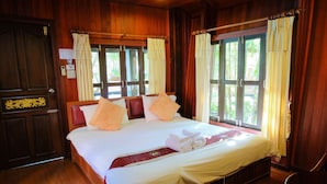 A wooden-paneled room with a large bed, two windows with curtains, and a wooden door. - Naya Resort (Tha Yang)