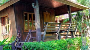 A wooden house with a porch, steps, and a small garden with flowers. - Naya Resort (Tha Yang)