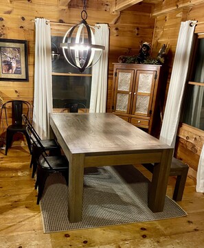Ein Holzespeisetisch mit Stühlen, eine Hängelampe und ein Schrank mit dekorativen Verzierungen.