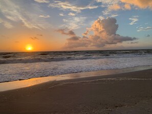 Uma praia com ondas e um pôr do sol.
