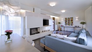 Ein modernes Wohnzimmer mit Kamin, einer Couch und einem Fernseher.