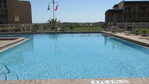 A rectangular pool with a 3 FT 3 IN depth marker, surrounded by a wooden fence, lounge chairs, and a building with balconies in the background.