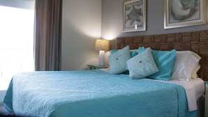 A bedroom with a bed, a nightstand, a lamp, and two framed pictures on the wall.