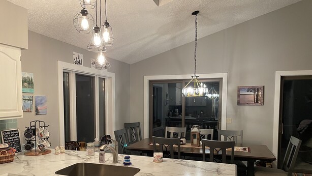 Een moderne keuken met een groot eiland, een eethoek en uitzicht op de woonkamer.