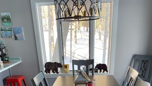 Een eetruimte met een lange houten tafel, rode en zwarte stoelen, een kerstgedekte tafelmat, kaarsen en een decoratieve lantaarn.