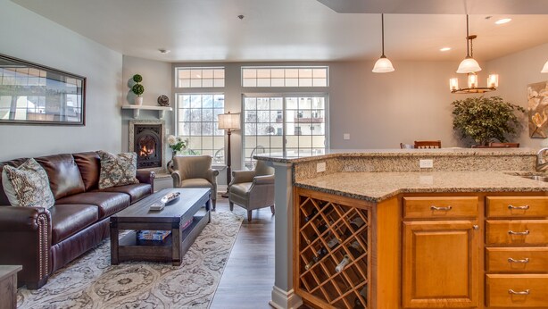 Una cocina moderna con una alacena para vinos integrada, un comedor con chimenea y una sala de estar con sofá de cuero y mesa de centro.
