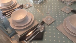 A dining table set with plates, bowls, cutlery, and a bottle of champagne. - SEASIDE COTTAGE WITH SEA VIEWS (Newbiggin-by-the-Sea)