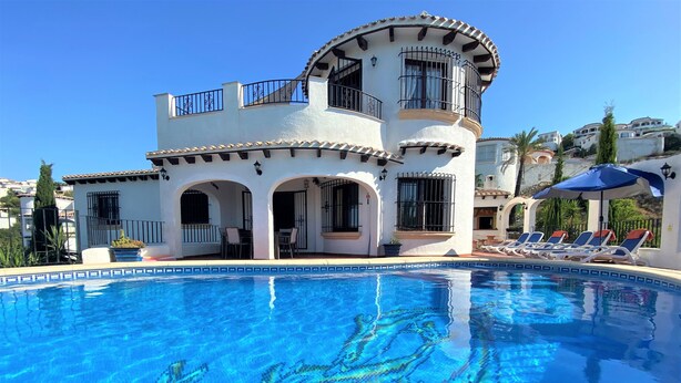 Un edificio de dos pisos con piscina, que presenta un balcón curvo y un borde de piscina con azulejos.