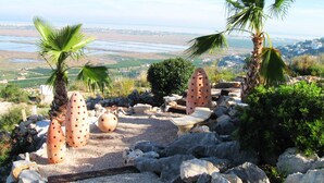 Un jardín con palmeras, una mesa de piedra y vistas a un paisaje costero.