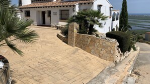 Una villa de estilo mediterráneo con techo de tejas, paredes de piedra y un camino empedrado que conduce a la entrada.