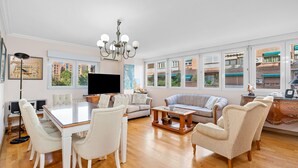 A spacious living room with a large TV, comfortable seating, and a view of buildings through large windows. - AIR CONDITIONING, PORTER, CORNER, CENTRAL, WIFI, WIDE EQUIPPED ALL (Granada)