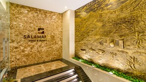 A hotel lobby with a marble wall, a large mural, and a staircase. - Salamander Hotel and Apartment (Da Nang)