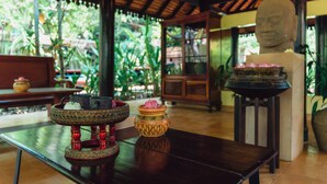 A traditional room with a wooden table, a decorative bowl, and a statue. - Pandora Suite D'Angkor (Siem Reap)