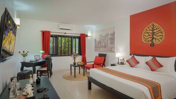 A hotel room with a bed, a desk, a chair, a table with a tray, and a window with curtains.