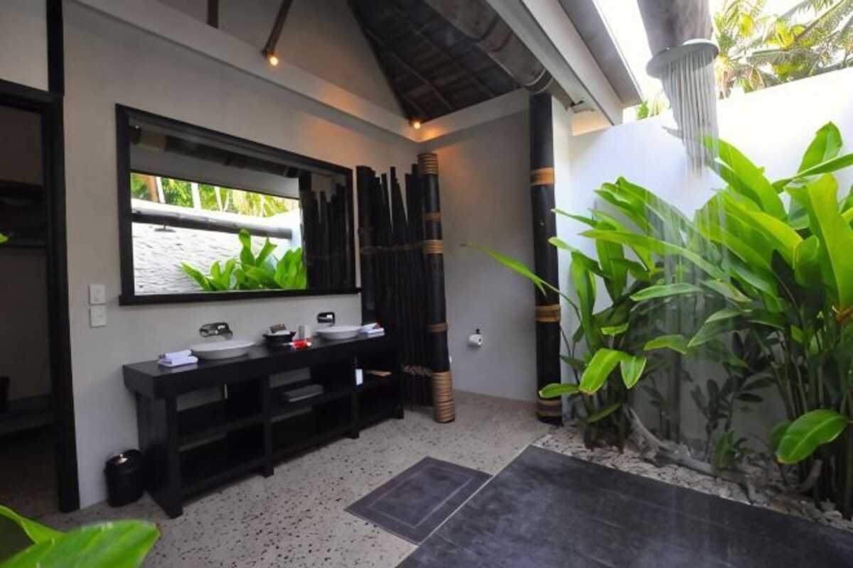 Un baño con un espejo grande, dos lavamanos, un mueble de tocador negro y un pequeño acuario.