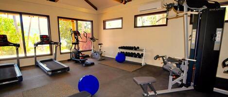 A gym with treadmills, an elliptical, a bench, a squat rack, and dumbbells.