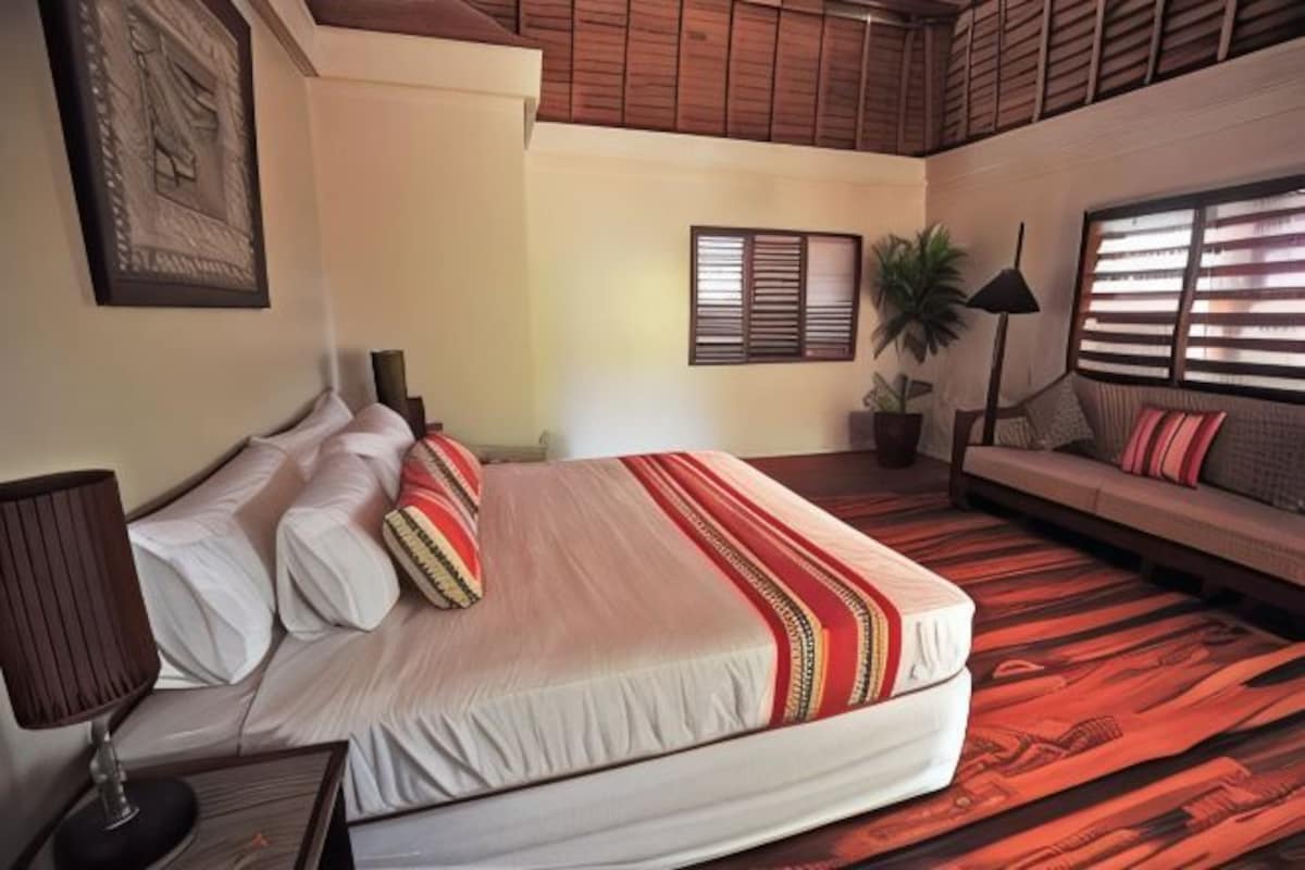 Un dormitorio con cama, sofá, lámpara, planta en maceta y ventana con persianas.