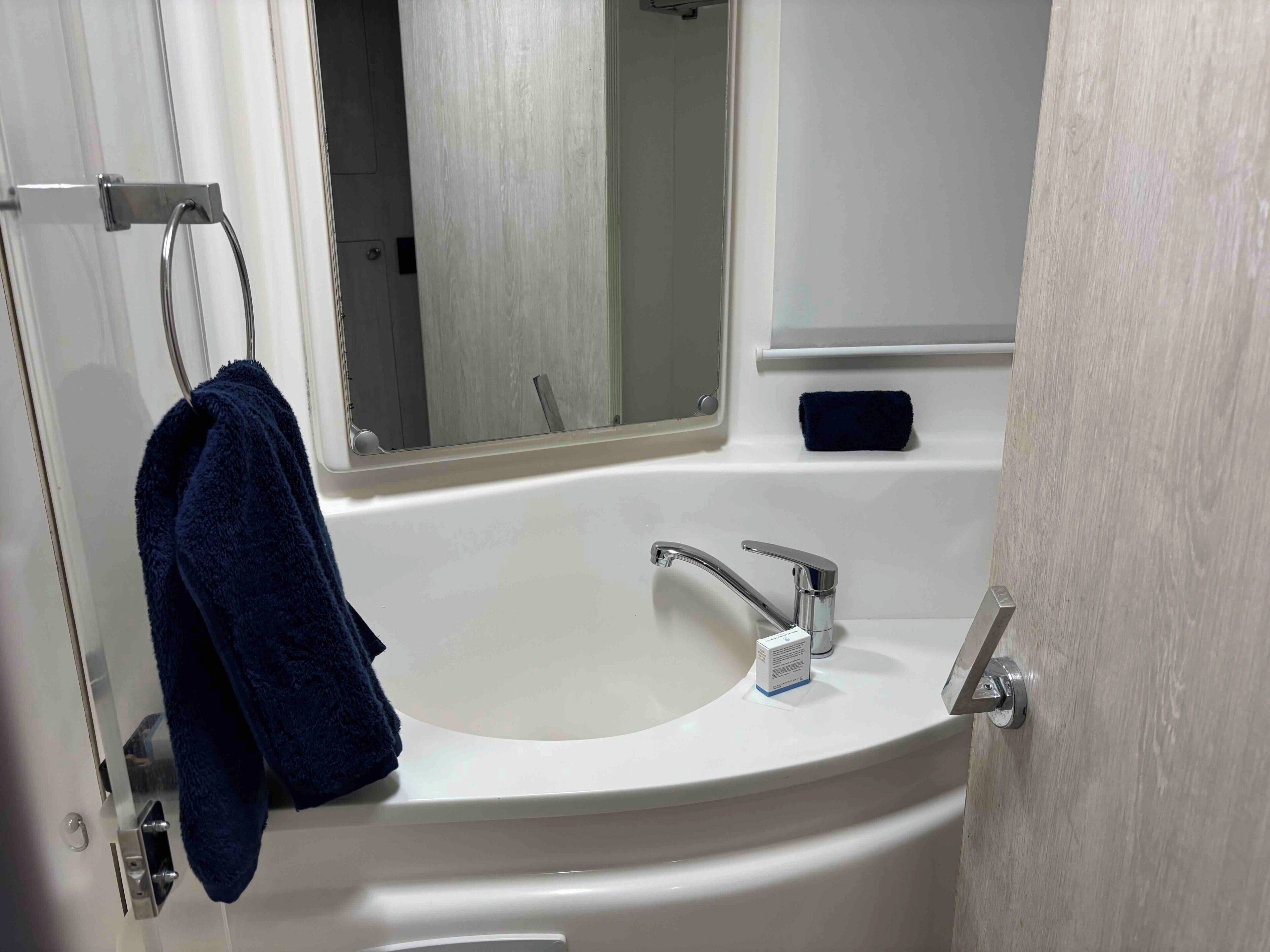 A bathroom with a white sink, a mirror, and a towel hanging on a rack.