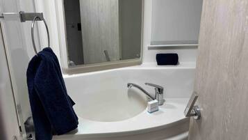 A bathroom with a white sink, a mirror, and a towel hanging on a rack.