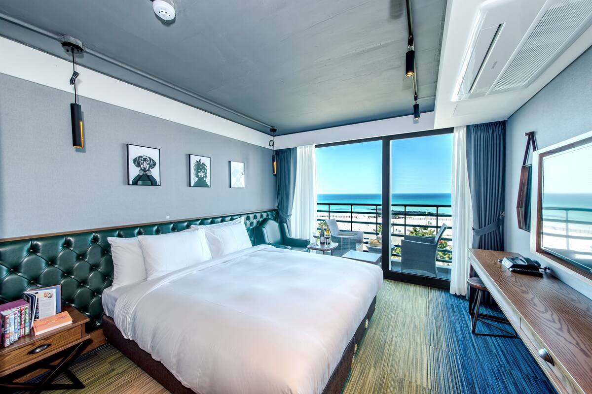 A hotel room with a large bed, a desk, and a view of the ocean.