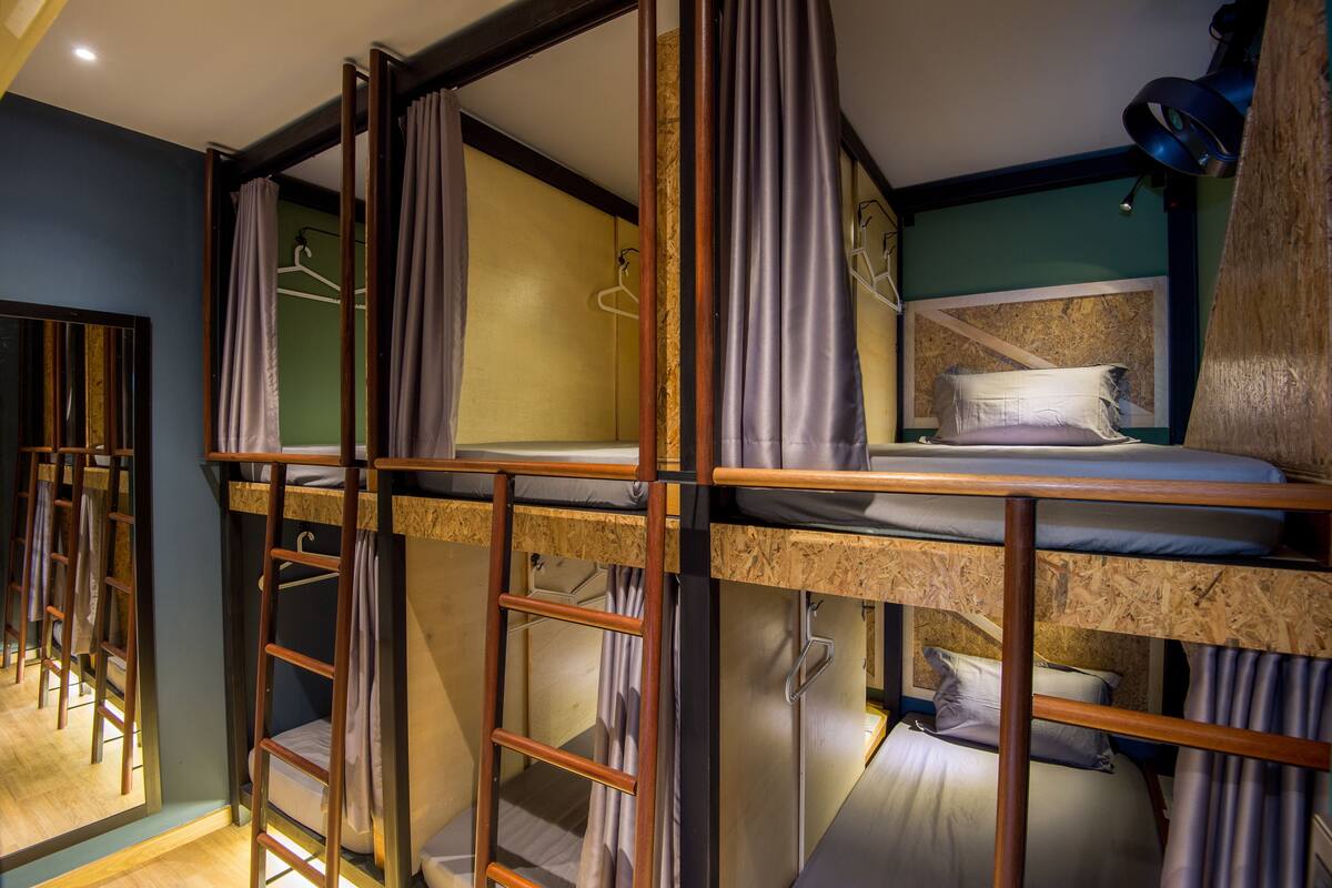 A bunk bed room with wooden railings, a headboard, and a hanging light fixture.