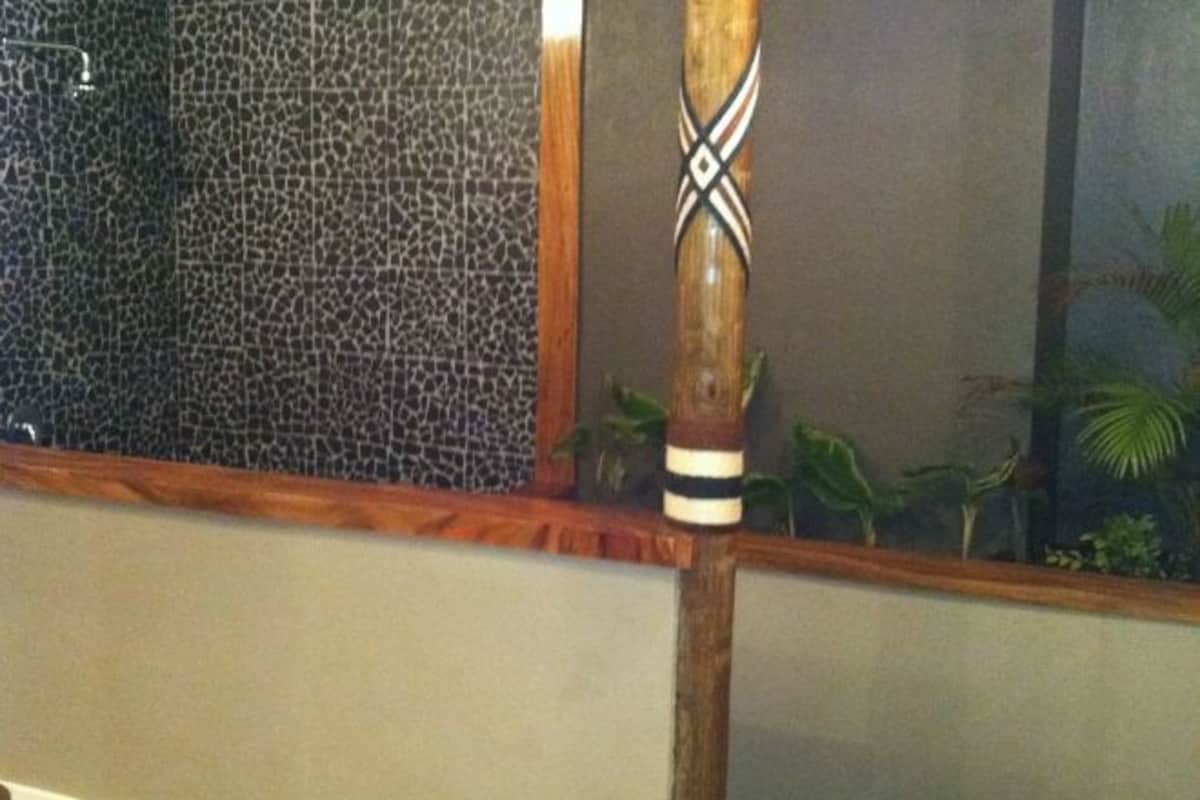 A wooden pillar with a decorative pattern, a textured wall, and a small plant.