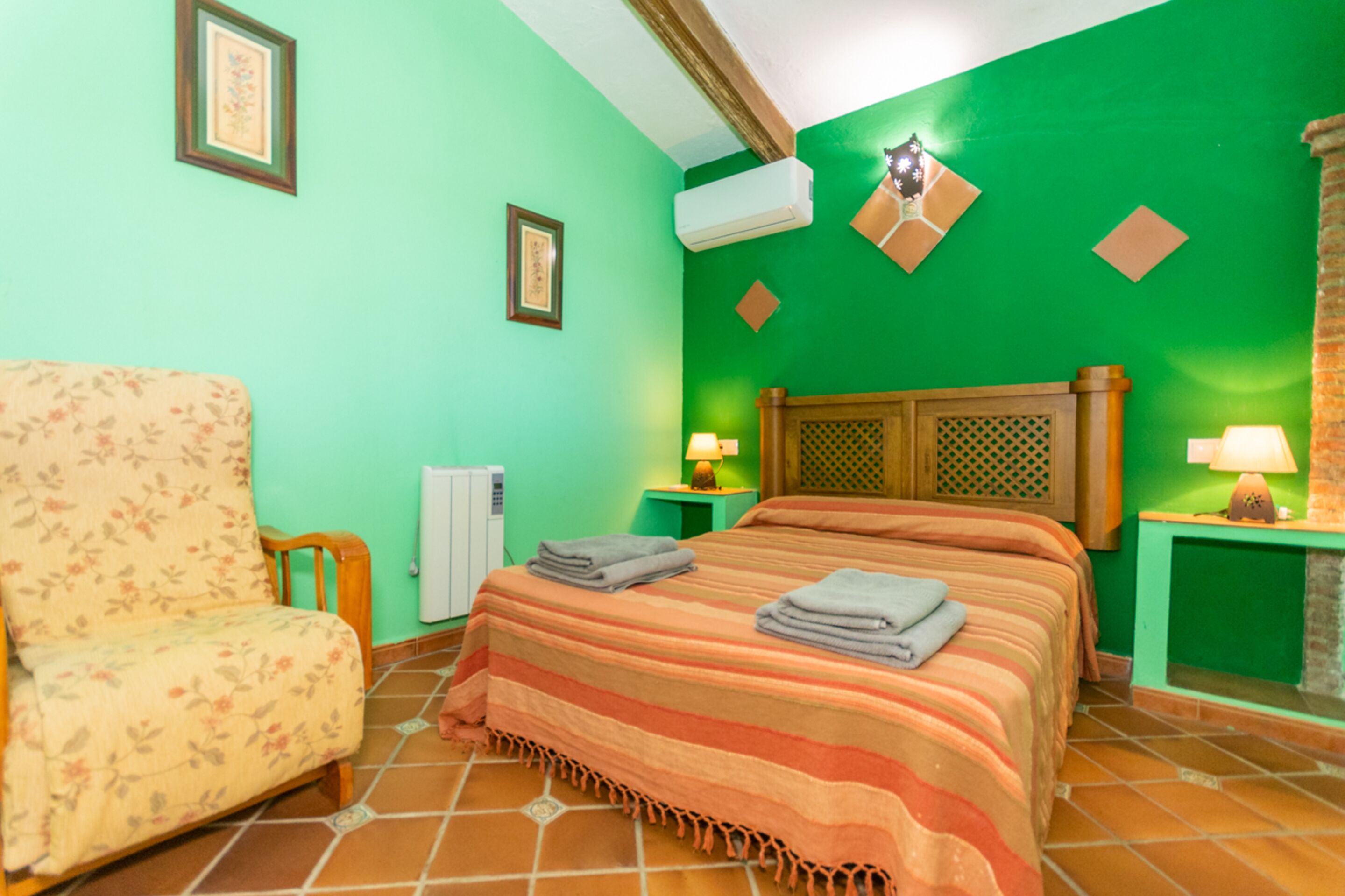 Un dormitorio con cama, una silla y un radiador.
