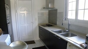 A compact kitchen with a washing machine, a sink, and a door.