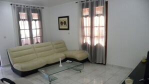 A living room with a beige sofa, a glass coffee table, and a black side table.