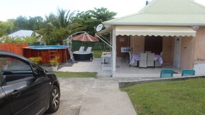 A house with a covered patio, a swimming pool, and a car parked in the driveway.