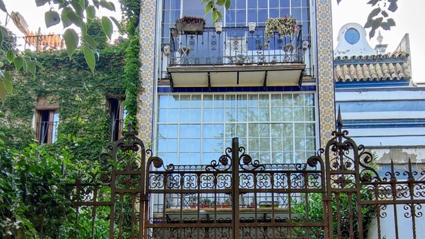 A building with a balcony, a wrought iron gate, and potted plants.