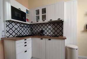 A compact kitchen with white cabinets, a microwave, and a coffee maker.