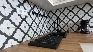 A kitchen with patterned tiles, a coffee maker, and a black rack.