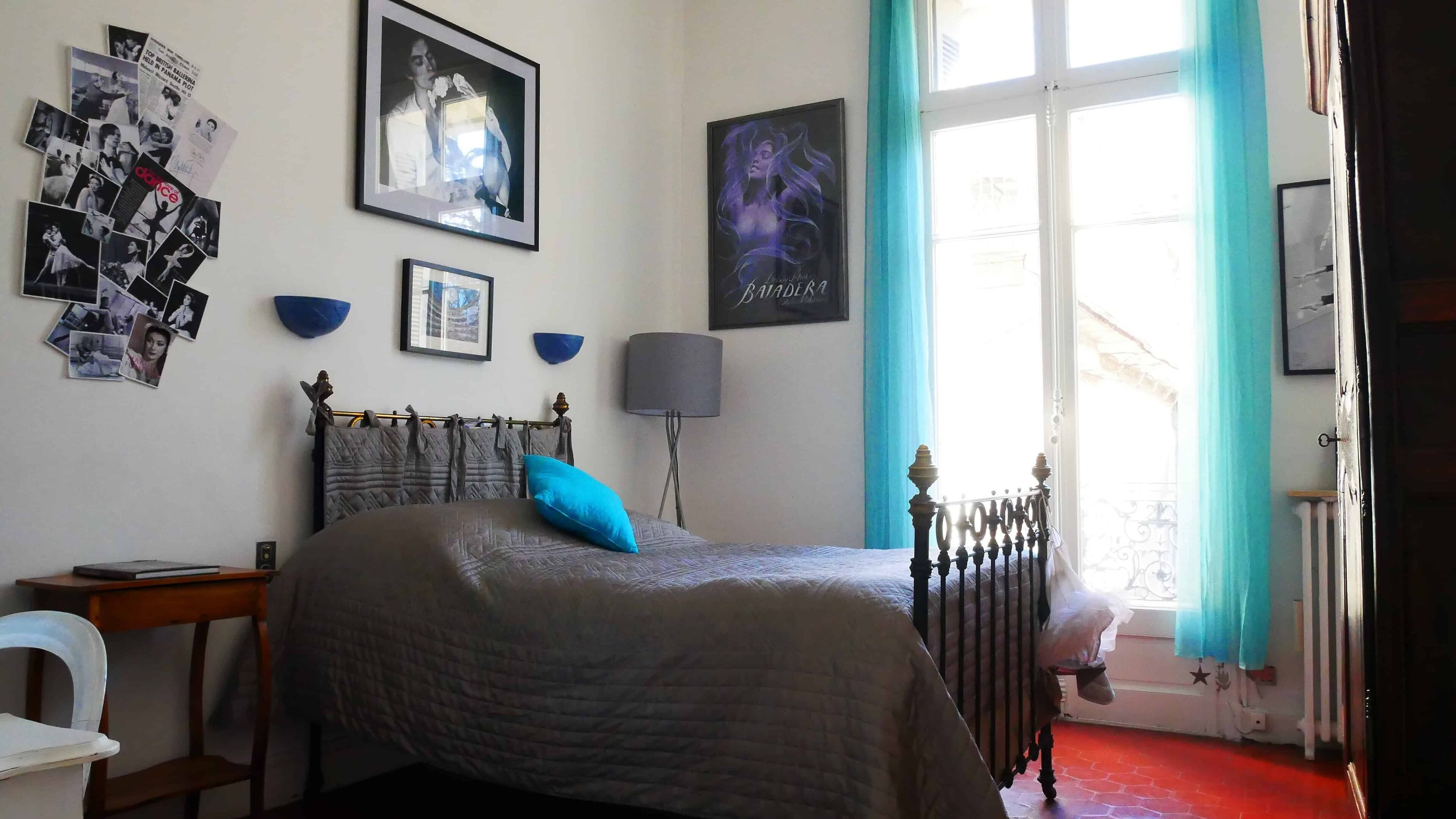 Un dormitorio con cama, mesita de noche, lámpara y ventana con cortinas.