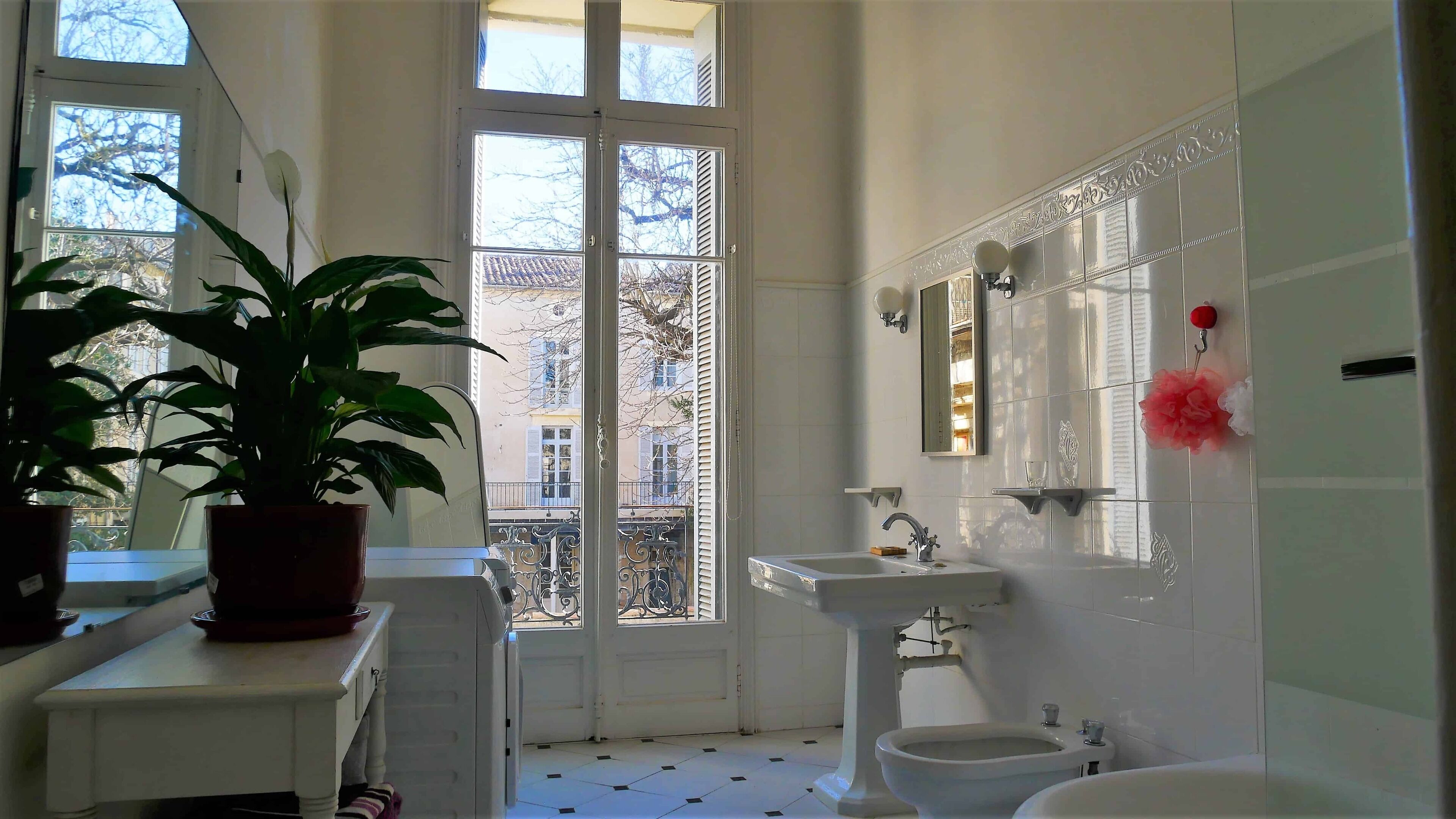 A bathroom with a large window, a sink, a toilet, and a potted plant.