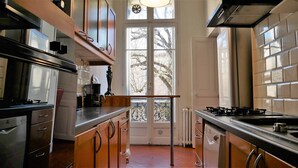 A kitchen with stainless steel appliances, wooden cabinets, and a view of trees through a large window. - "Diva"' apartment with unique atmosphere in a prime location (Nîmes)