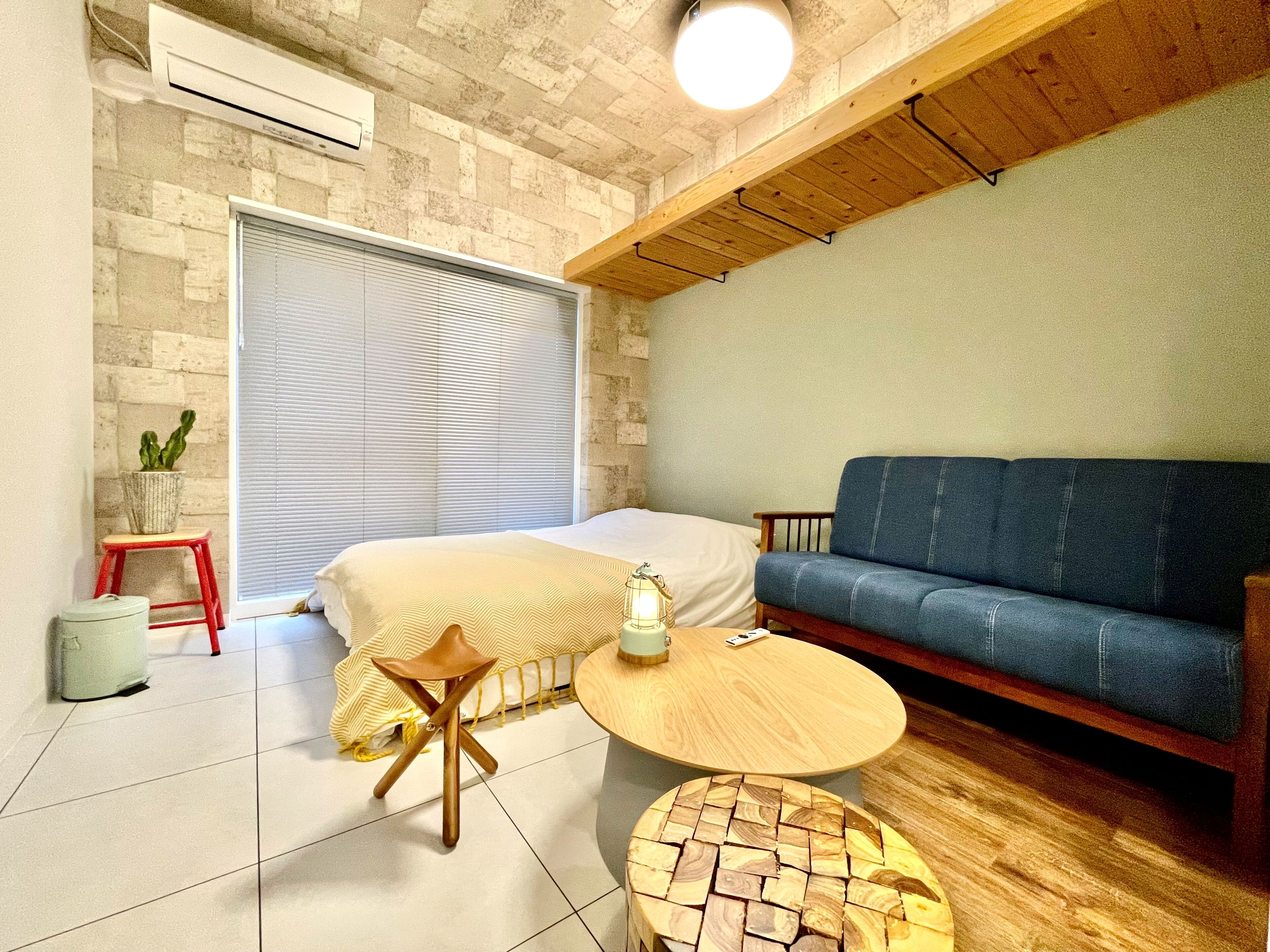 Una habitación acogedora con una cama, un sofá azul, una mesita redonda y una planta en maceta.