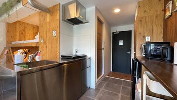 A compact kitchen with a stainless steel island, a microwave, and a coffee maker on the counter.