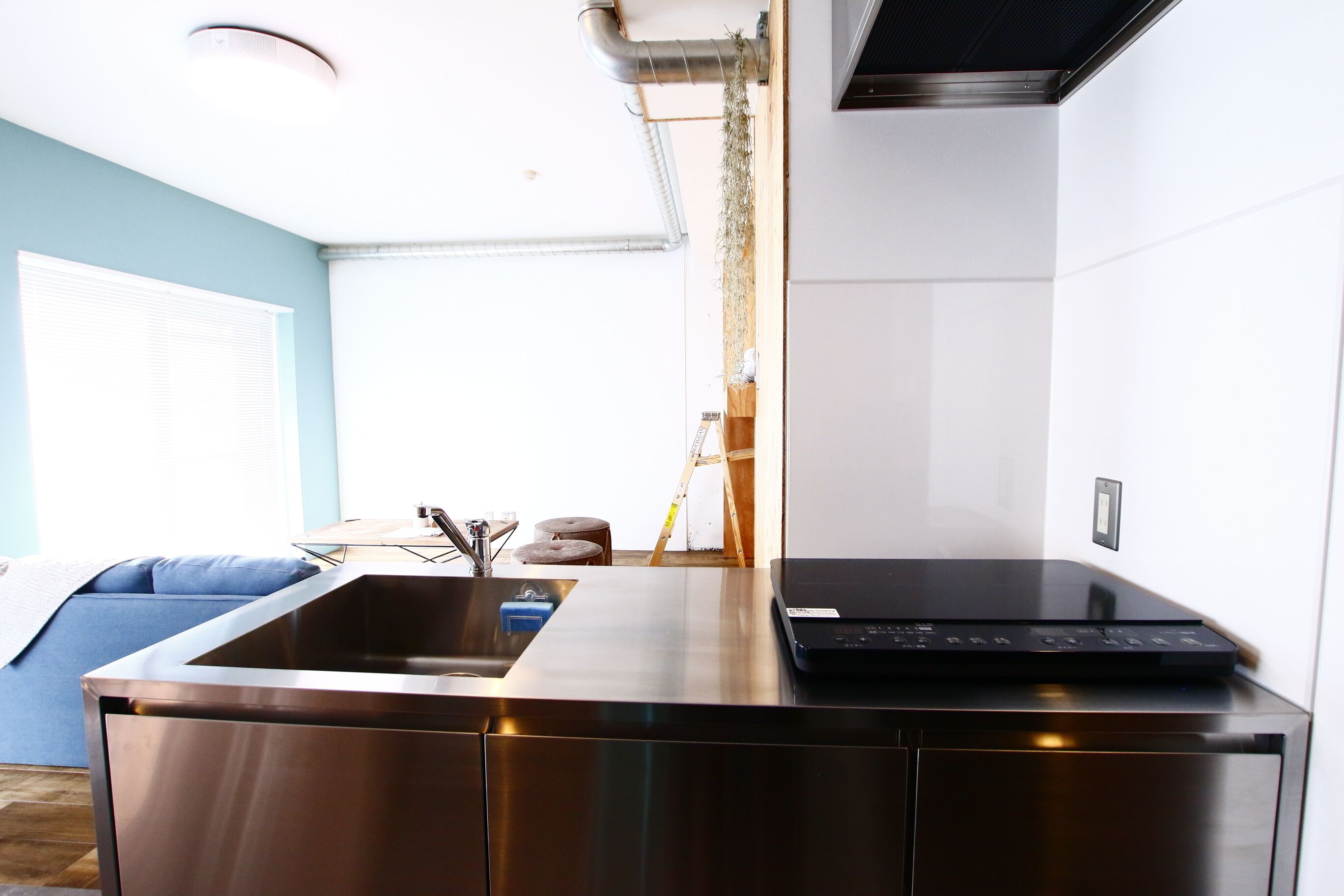 A modern kitchen with stainless steel appliances, a built-in sink, and a laptop on the countertop.