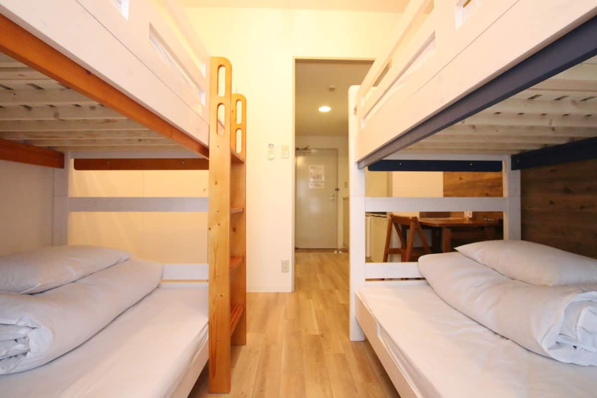 A bunk bed room with wooden headboards, a wooden table, and a door leading to another room.