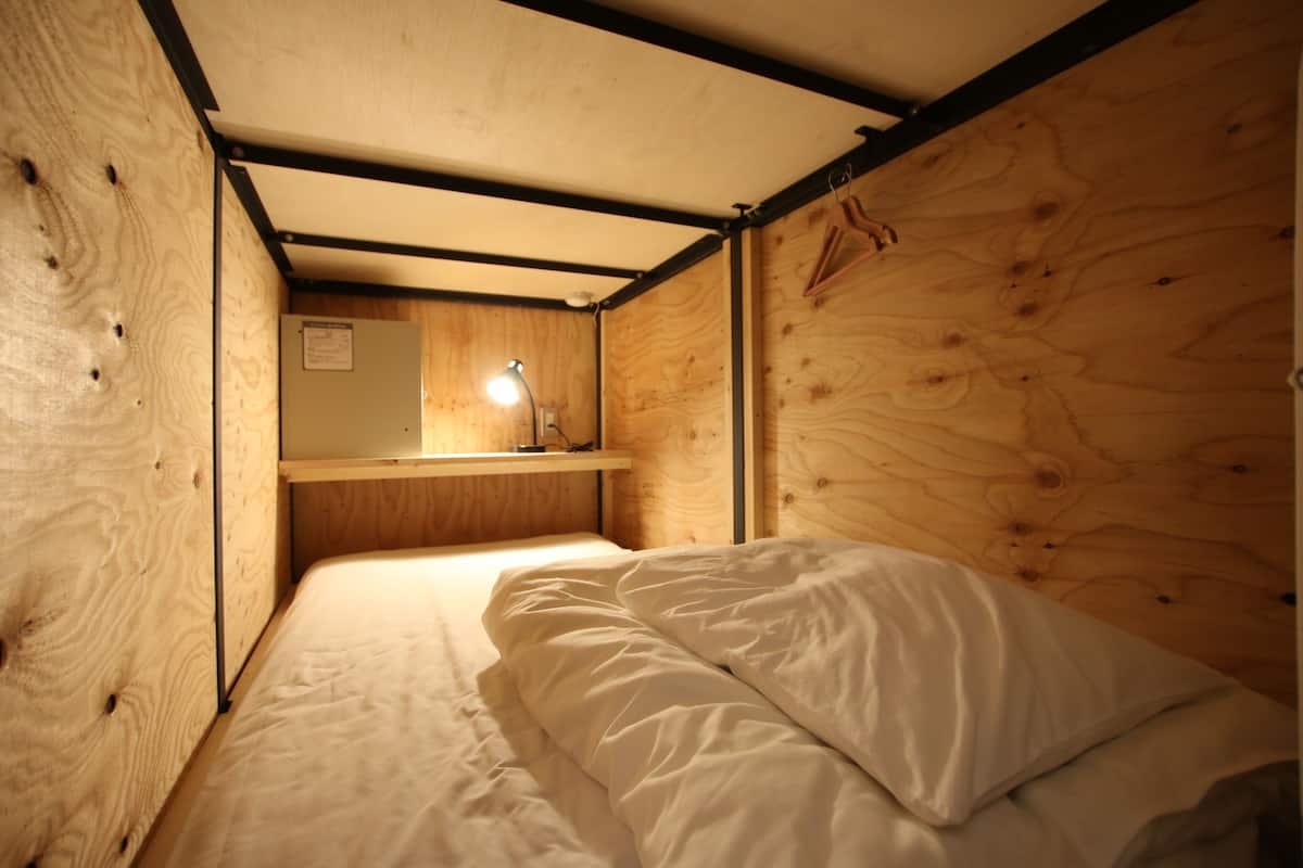 A small, wooden room with a bunk bed, a small shelf, and a mirror.