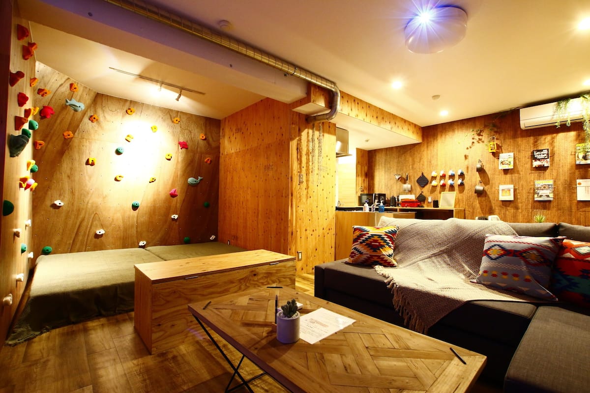 A cozy room with a climbing wall, a sofa, and a wooden table.