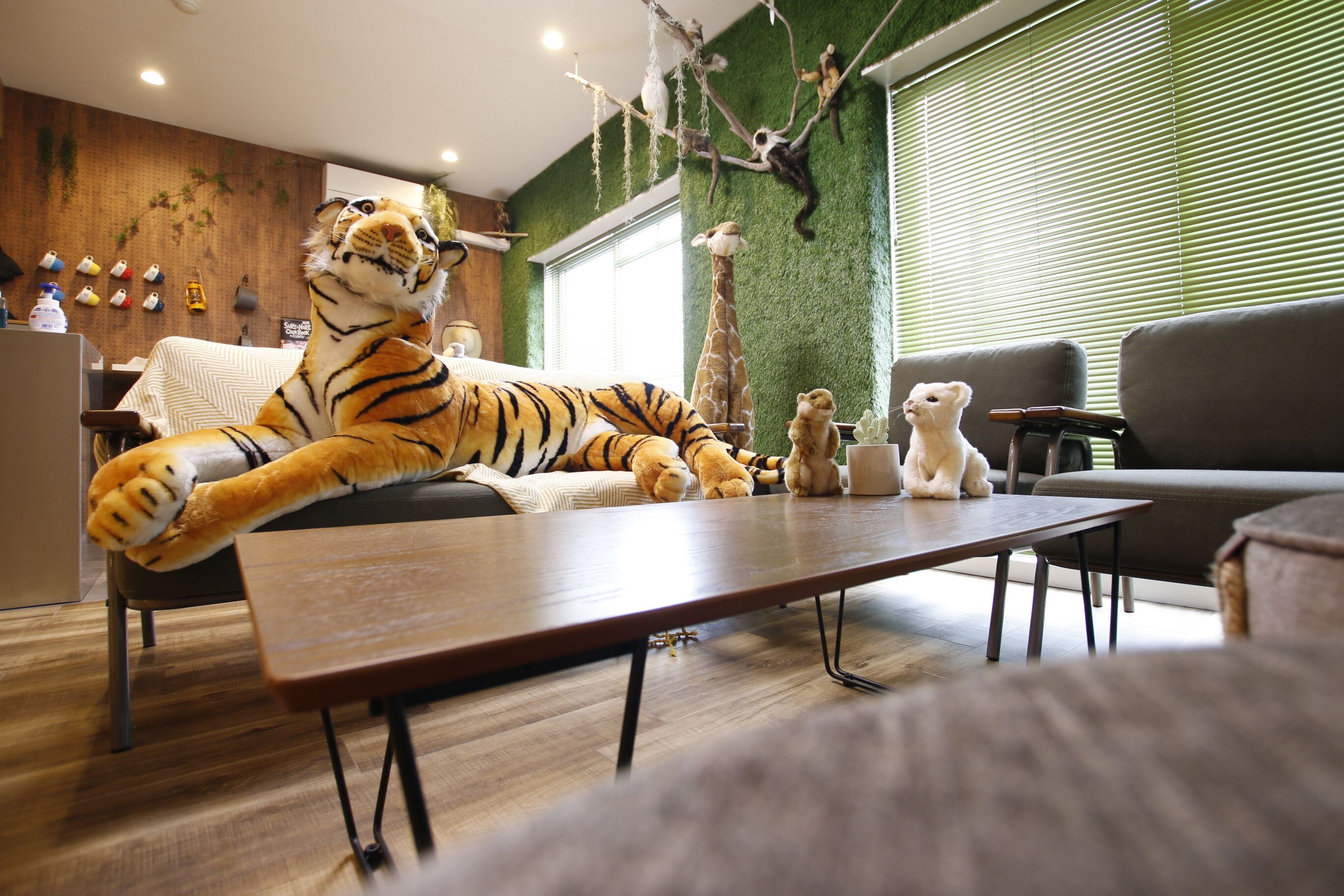 Uma sala de estar com um brinquedo de pelúcia de tigre sobre uma mesa, uma girafa e um urso em um sofá.