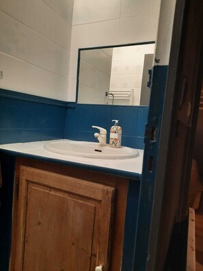 Ein Badezimmer mit weißem Waschbecken, blauen Wandfliesen, einem Holzkästen und einem Spiegel über dem Waschbecken.