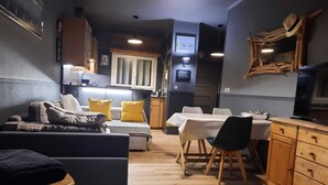 Un espace de vie compact comprenant un canapé, une table à manger et une kitchenette.