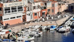 Un port de plaisance avec des bateaux amarrés et un bâtiment portant l’enseigne « Chez Fonfon ».