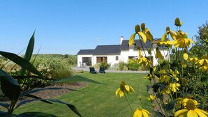 A house with a well-maintained lawn and a garden with yellow flowers.