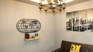 A modern living room with a chandelier, a globe artwork, a cityscape painting, a sofa, and a coffee table with bottles. - First Place B&B - Hualien Railway Station (Hualien City)