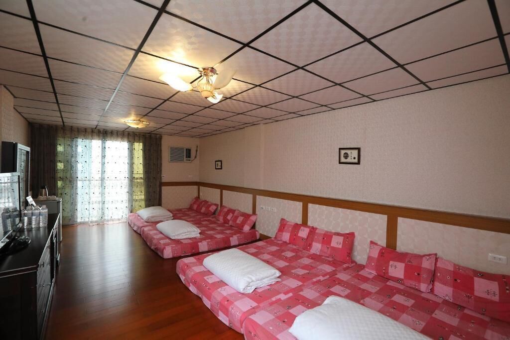 Ein Hotelzimmer mit zwei Betten, einem Fernseher und einem Fenster mit Vorhängen.